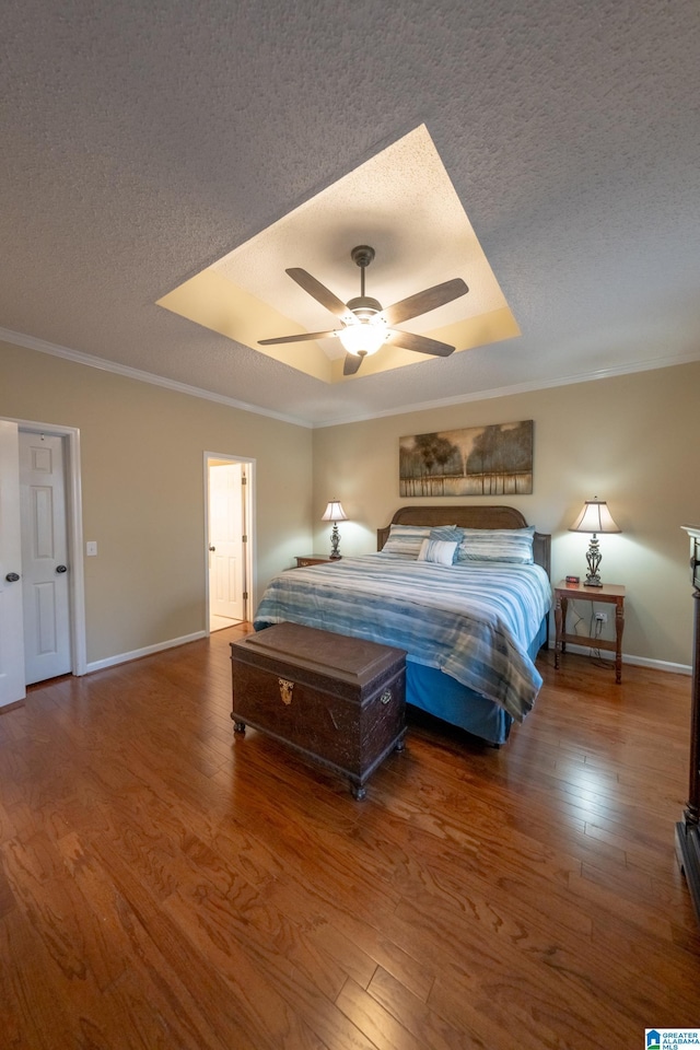 bedroom featuring wood-type flooring, ornamental molding, ceiling fan, a tray ceiling, and a textured ceiling