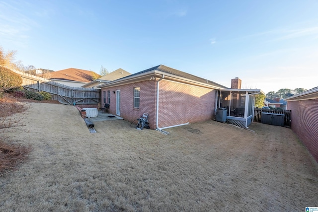 rear view of house with central AC unit, a patio area, and a sunroom