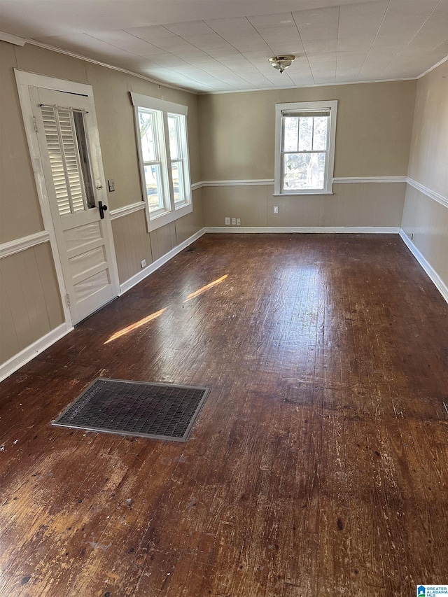 empty room with a wealth of natural light and dark hardwood / wood-style floors