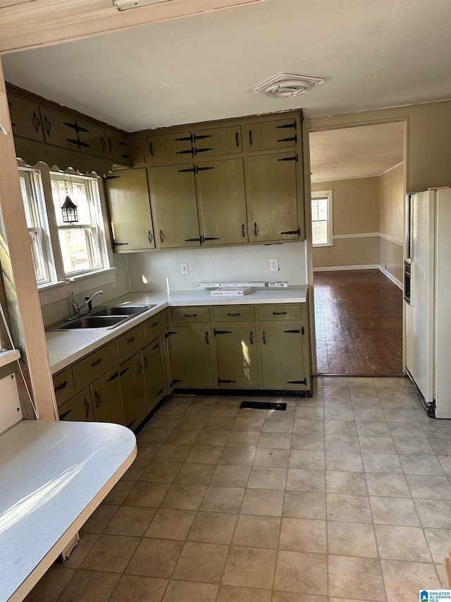 kitchen featuring green cabinetry, sink, and white fridge with ice dispenser