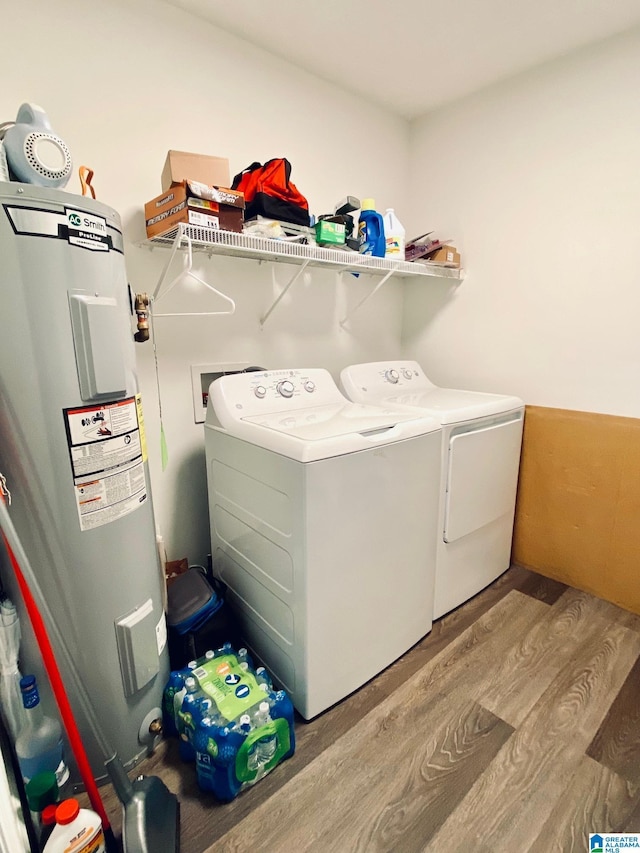 clothes washing area with washer and dryer, water heater, and light hardwood / wood-style flooring