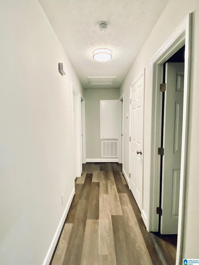 corridor with dark hardwood / wood-style floors and a textured ceiling