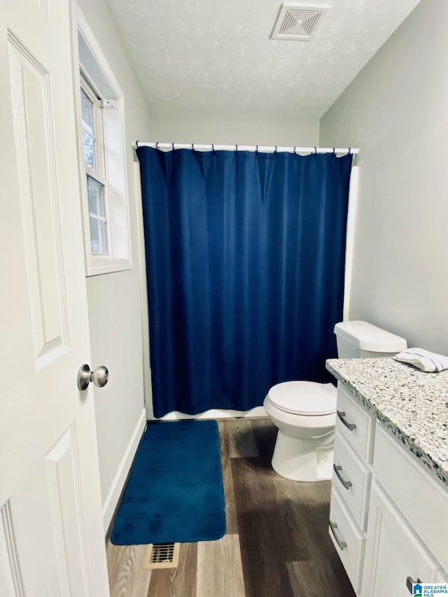 bathroom with wood-type flooring, vanity, toilet, a textured ceiling, and a shower with curtain