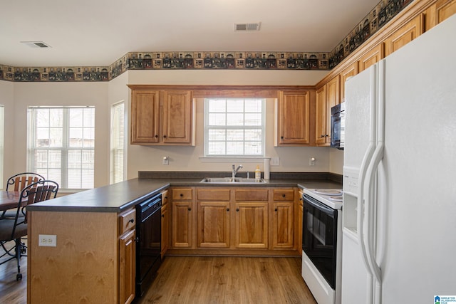 kitchen featuring light hardwood / wood-style floors, sink, black appliances, and kitchen peninsula