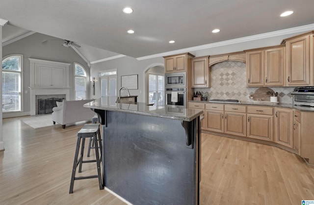 kitchen with stainless steel appliances, an island with sink, a fireplace, and a kitchen bar