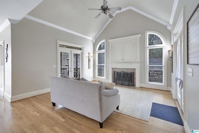 living room with a brick fireplace, ornamental molding, light hardwood / wood-style floors, and french doors