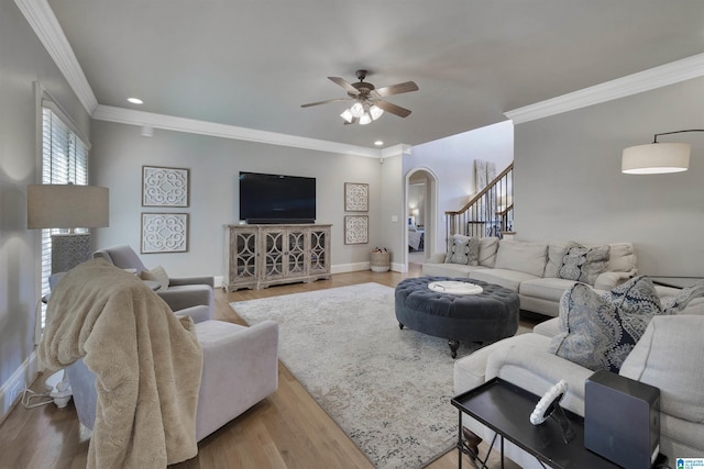 living room with light hardwood / wood-style flooring, ornamental molding, and ceiling fan