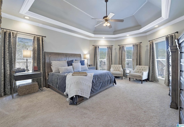 carpeted bedroom featuring multiple windows, ornamental molding, ceiling fan, and a tray ceiling