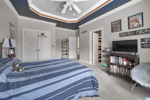 carpeted bedroom with ornamental molding, a tray ceiling, and a closet