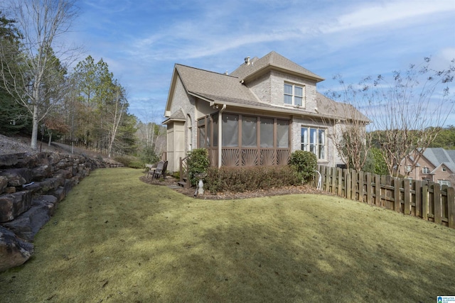 rear view of property with a sunroom and a yard