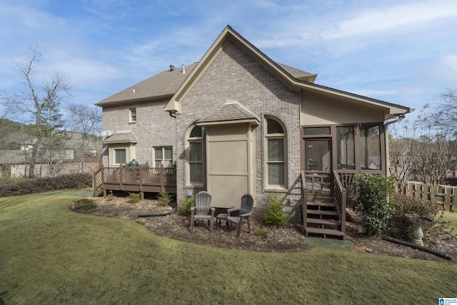 rear view of property with a wooden deck, a lawn, and a sunroom