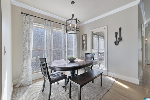 dining space with a notable chandelier, crown molding, and light hardwood / wood-style flooring