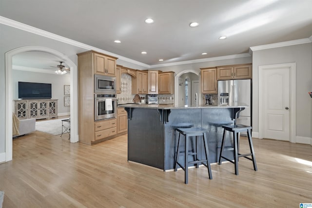 kitchen featuring a kitchen bar, stainless steel appliances, light hardwood / wood-style floors, and a kitchen island