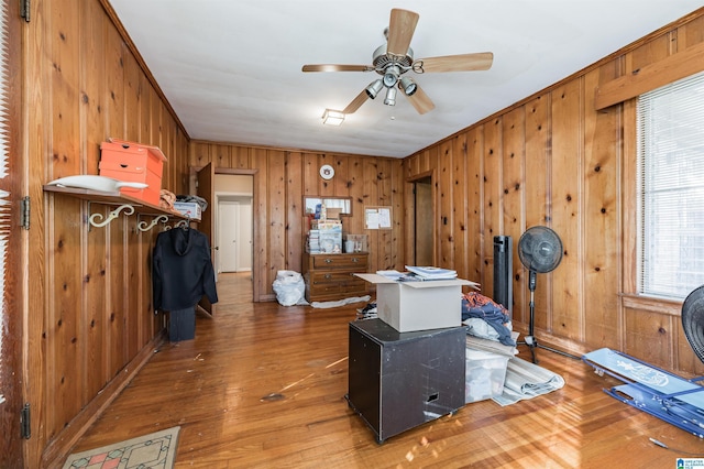 misc room featuring hardwood / wood-style floors, ceiling fan, and wood walls