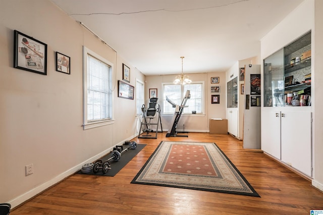 workout area with a chandelier and light hardwood / wood-style flooring