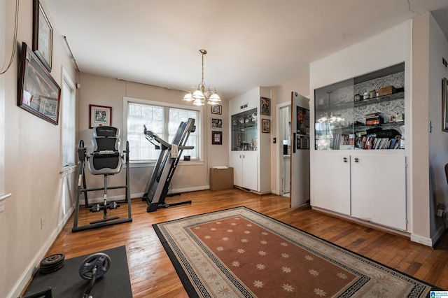 exercise room with light hardwood / wood-style flooring and a chandelier