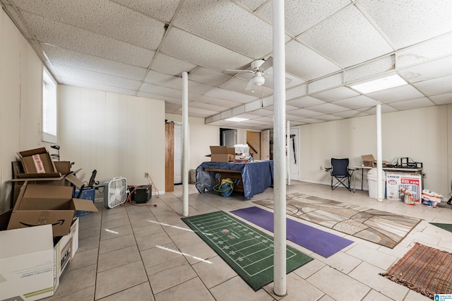 basement with a paneled ceiling, tile patterned floors, and ceiling fan