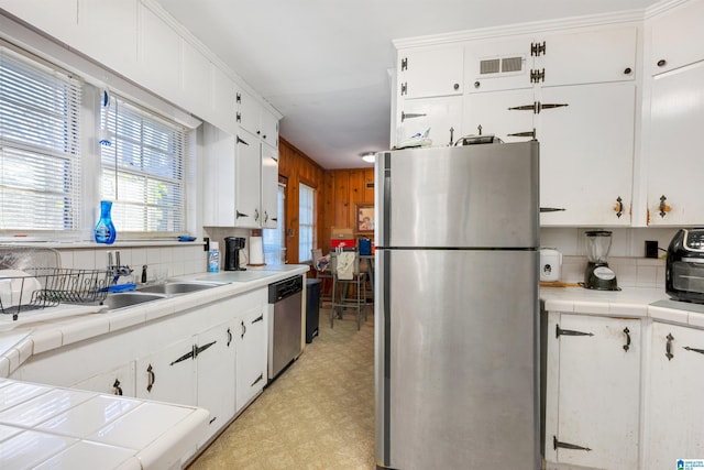 kitchen with sink, white cabinets, decorative backsplash, tile counters, and stainless steel appliances