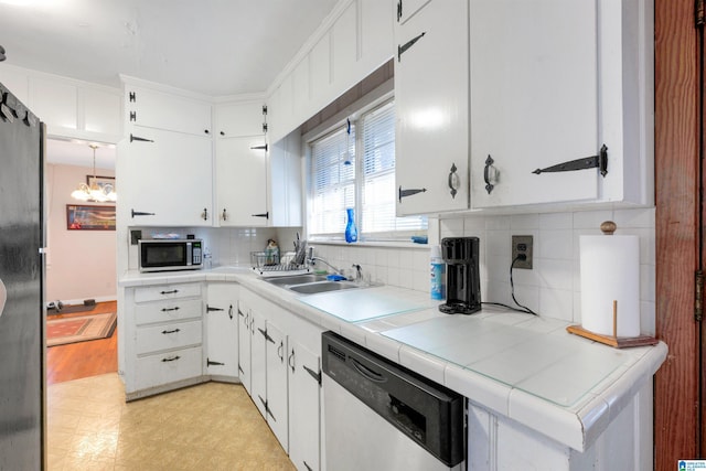 kitchen featuring appliances with stainless steel finishes, tile counters, and white cabinets