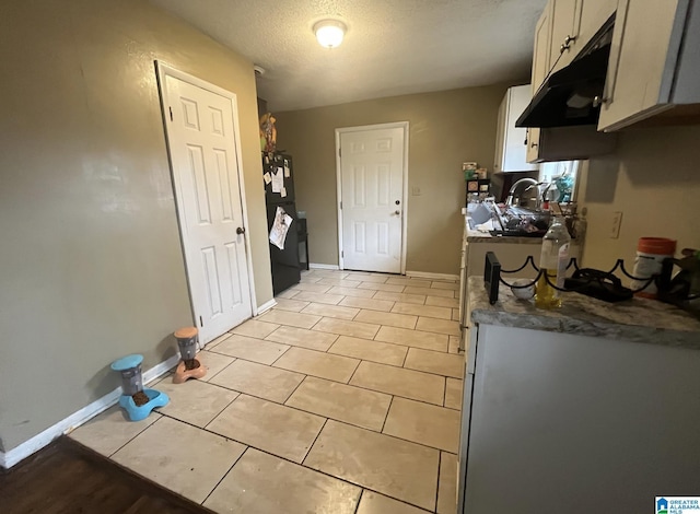 kitchen with black fridge, light tile patterned flooring, and a textured ceiling