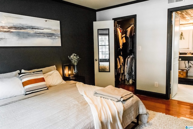 bedroom featuring hardwood / wood-style flooring, a walk in closet, ensuite bathroom, and a closet