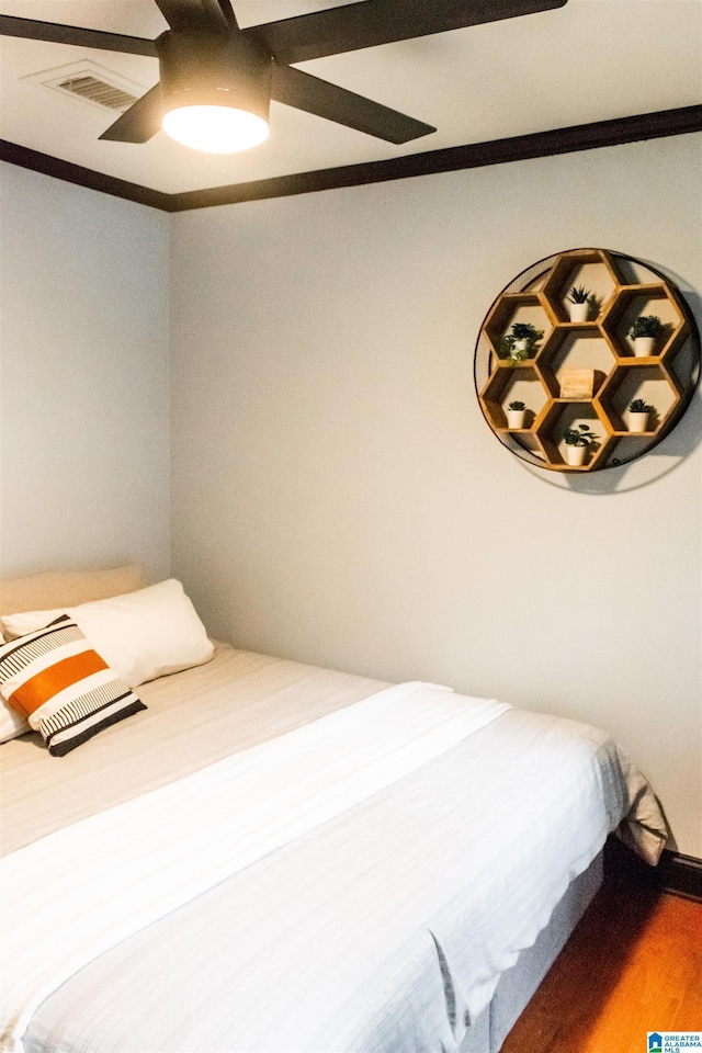 bedroom with hardwood / wood-style floors, crown molding, and ceiling fan