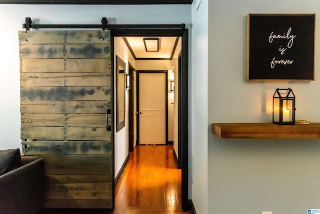 hallway with a barn door and hardwood / wood-style floors