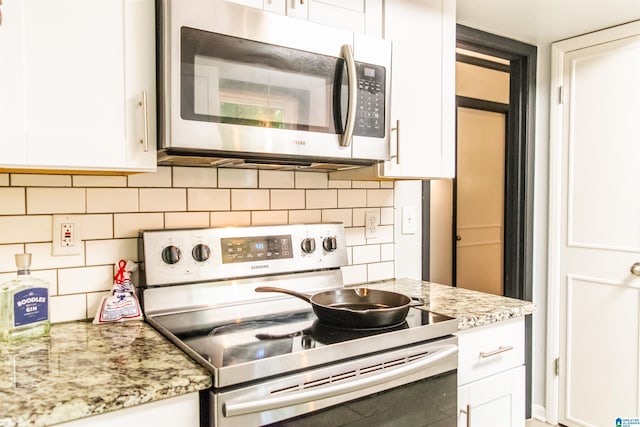 kitchen with backsplash, appliances with stainless steel finishes, light stone countertops, and white cabinets