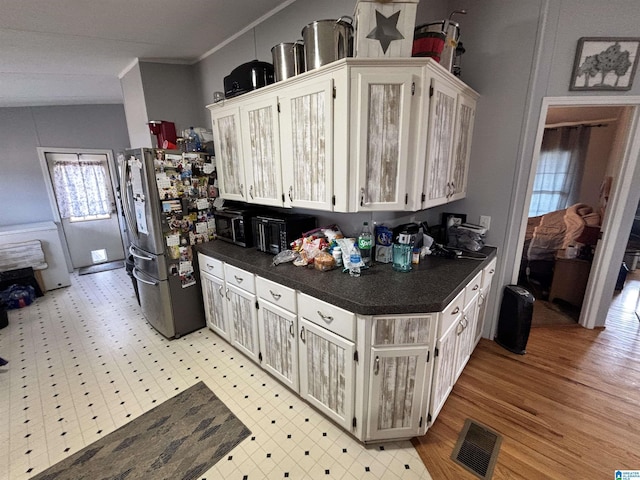 kitchen featuring crown molding, stainless steel fridge, and white cabinets