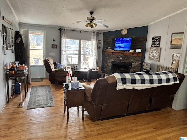 living room featuring crown molding, ceiling fan, a fireplace, and light hardwood / wood-style floors