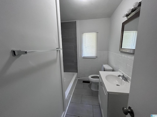 bathroom with tile walls, tiled shower, vanity, tile patterned floors, and toilet