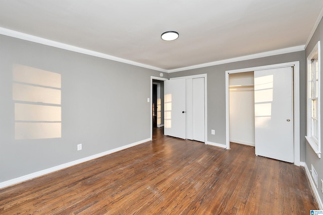 unfurnished bedroom with multiple closets, ornamental molding, and dark hardwood / wood-style floors