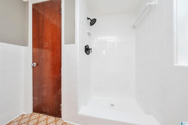 bathroom with a tile shower and tile walls