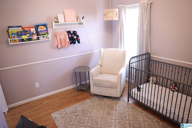 bedroom with wood-type flooring and a crib