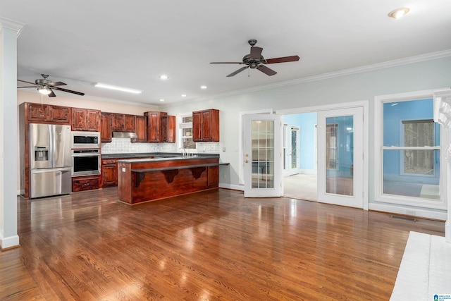 kitchen with tasteful backsplash, dark wood-type flooring, stainless steel appliances, and a kitchen island