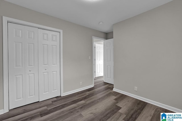 unfurnished bedroom with dark hardwood / wood-style flooring and a closet