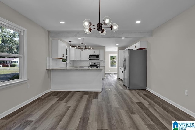 kitchen with hanging light fixtures, white cabinetry, appliances with stainless steel finishes, and kitchen peninsula