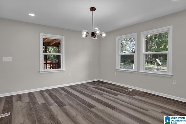 unfurnished room with a healthy amount of sunlight, dark hardwood / wood-style flooring, and a notable chandelier