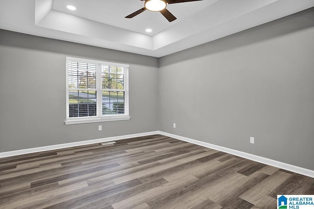 unfurnished room featuring wood-type flooring, a raised ceiling, and ceiling fan