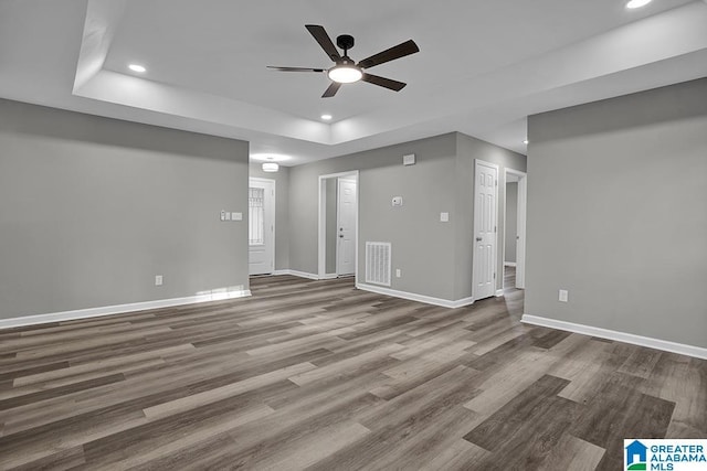 unfurnished living room with hardwood / wood-style flooring, ceiling fan, and a tray ceiling