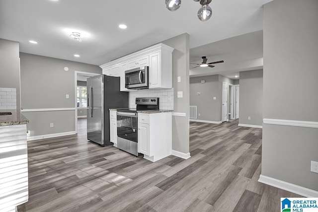 kitchen with backsplash, stainless steel appliances, light hardwood / wood-style floors, and white cabinets