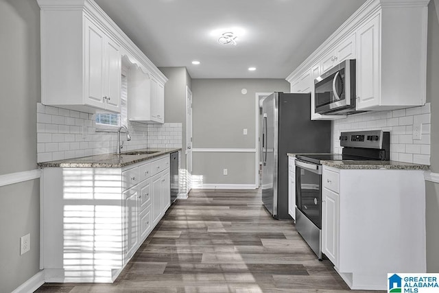 kitchen featuring sink, stainless steel appliances, dark stone counters, and white cabinets