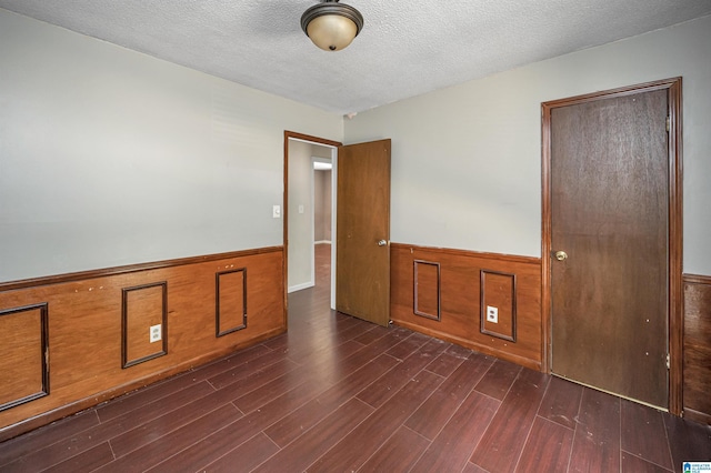 unfurnished room with dark wood-type flooring and a textured ceiling