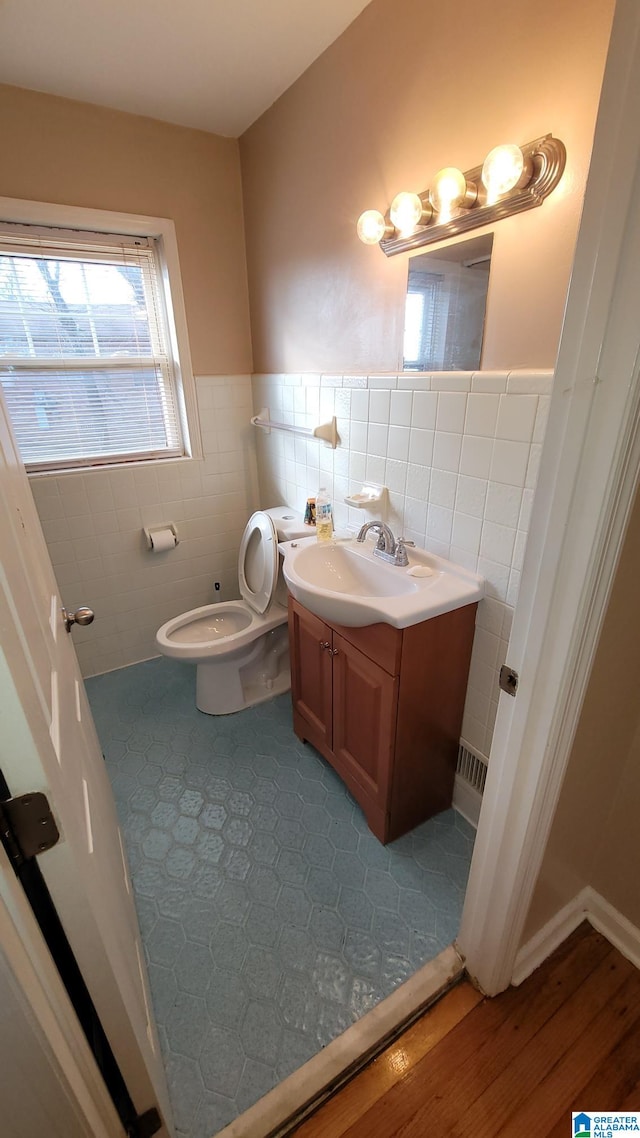 bathroom featuring vanity, tile patterned flooring, tile walls, and toilet