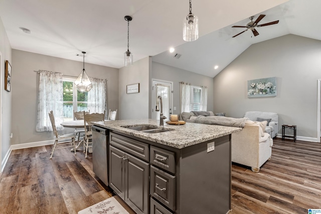 kitchen featuring sink, decorative light fixtures, dishwasher, an island with sink, and light stone countertops