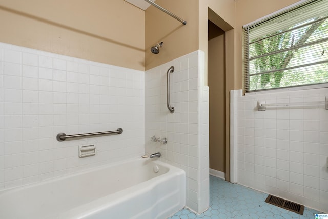 bathroom with tiled shower / bath combo and tile patterned flooring