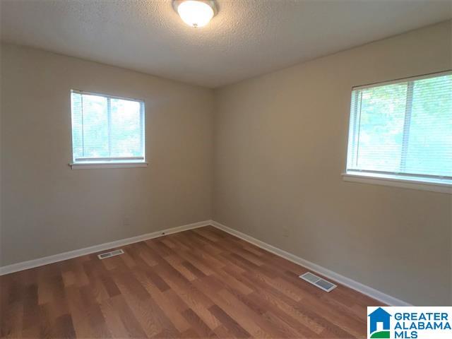 2838 Micmac Dr, Birmingham, AL 35215 - empty room featuring visible vents, a healthy amount of sunlight, and wood finished floors
