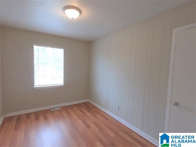 2838 Micmac Dr, Birmingham, AL 35215 - unfurnished room featuring baseboards, visible vents, a textured ceiling, and light wood-style floors