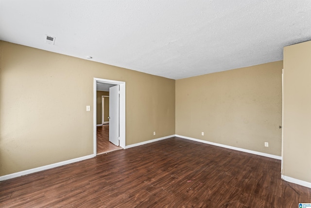 unfurnished room featuring dark wood-type flooring and a textured ceiling