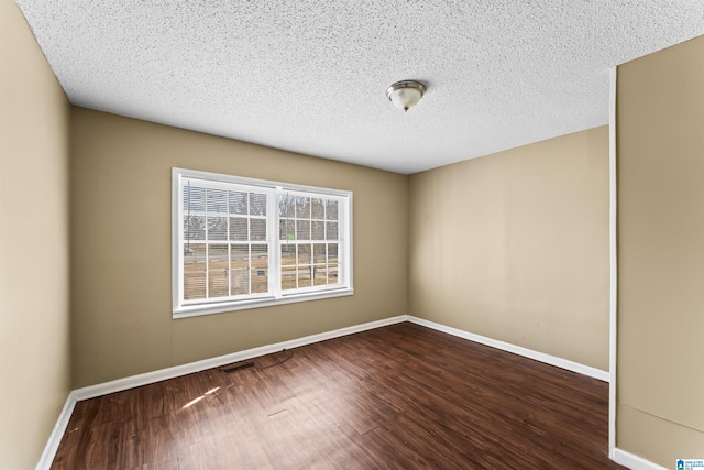 unfurnished room featuring dark wood-type flooring and a textured ceiling